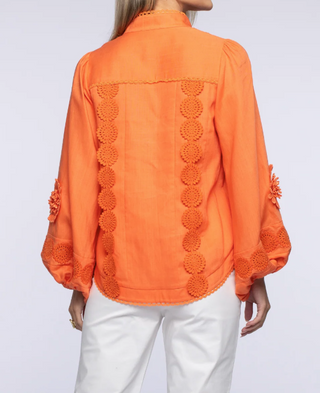 Orange blouse with decorative patterns on a plain background