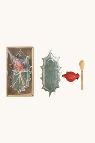 A Christmas-themed match set on a light cream background, featuring a green holly-shaped matchbox with a red bird and wooden match, a green holly-shaped ceramic dish, a small red bird dish, and a wooden spoon.