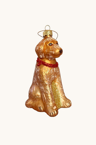 A gold-colored glass ornament shaped like a sitting dog, featuring a textured finish, a red glittery collar, and a gold hanging loop at the top, set against a plain off-white background.