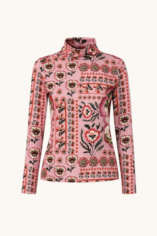 A pink long-sleeve mock-neck top with a detailed floral and botanical pattern in red, green, and black, displayed on a clean off-white background.