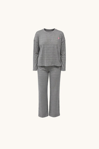 A two-piece pajama set featuring a long-sleeve top and matching pants in a gray and white horizontal stripe pattern, with a small pink embroidered logo on the left chest, shown against a plain off-white background.
