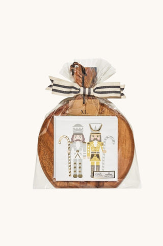 A round wooden serving board wrapped in clear cellophane and tied with a striped ribbon, featuring a printed nutcracker illustration on the front.