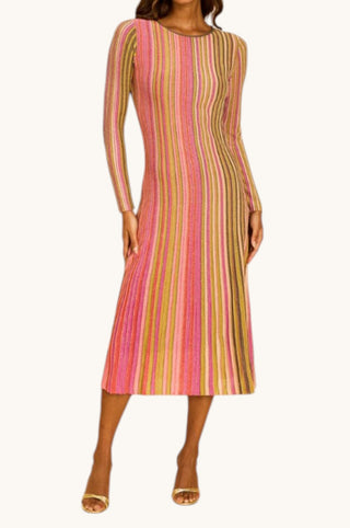 A woman modeling a long-sleeve midi dress with vertical multicolor stripes in pink, orange, yellow, and green on a plain light background.